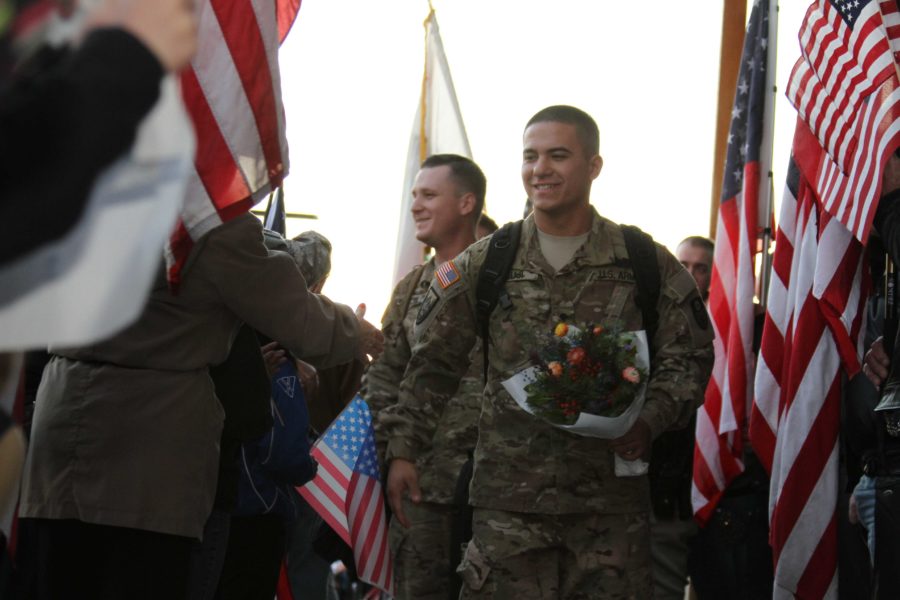 Veterans Troy Tsuji and Richard McKee walk through a crowd of flags and friends at
a locally planned party. They are two of nine soldiers returning home from war.