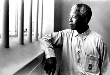 Mandela staring out of the prison cell which housed him for over 25 years.