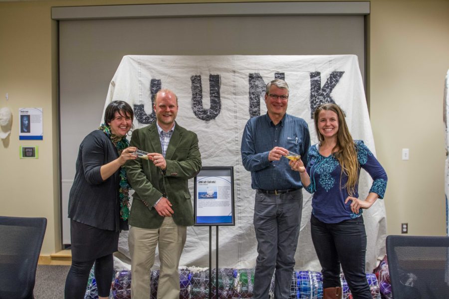 Speakers Jessica Jones, Denny Rosatti, David Bannister and Carolyn Box stand in front of a Junk Boat that is part of the Synthetic Seas exhibit after an open house presentation. The exhibit was lent by the 5 Gyres Institue to the Frank P. Doyle Library.