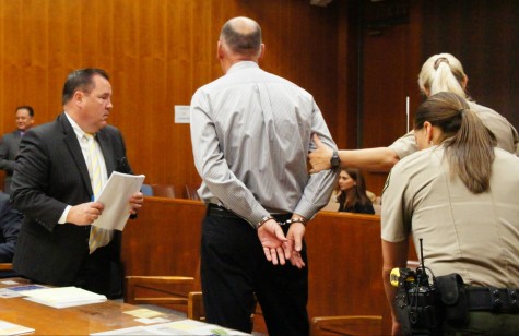 Deputies lead a handcuffed Holzworth from the courtroom May 29.