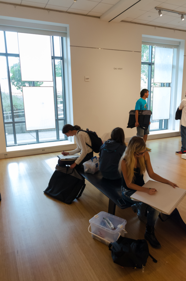 Students studiously sketching in the art gallery.