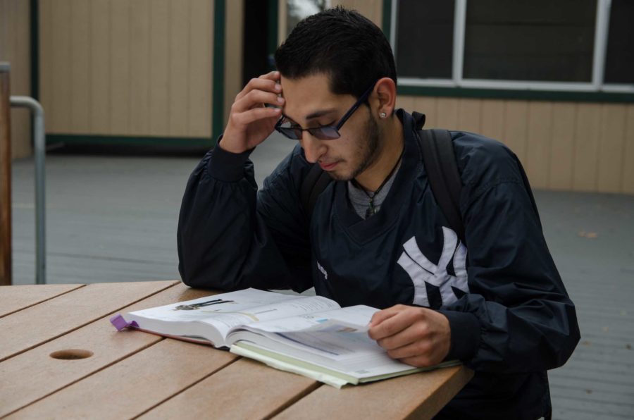 A student studies his textbook outside of class at SRJC at Analy Village.