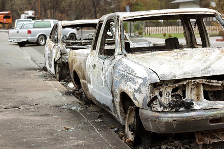 A line of vehicles remain parked after the fire spread from adjacent houses.