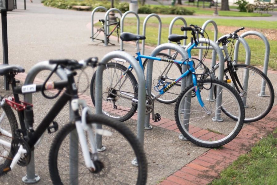 Student bikes stand idly in a bike rack outside of Plover Hall.