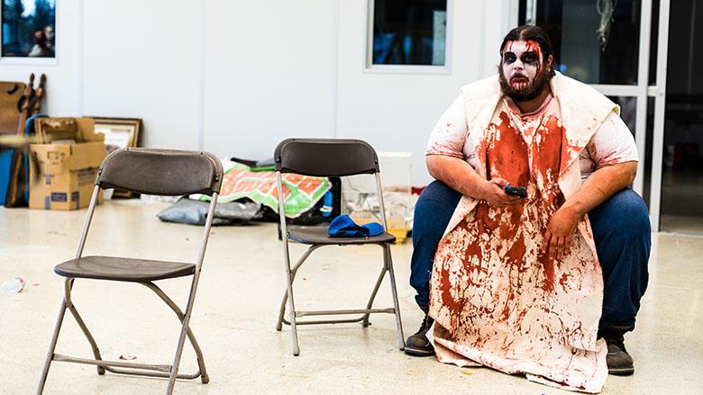 Nick Christenson, 30, an actor designated to a butcher shack-themed room in one of the haunted houses at Blind Scream, waits on his phone for the venue to begin admissions to visitors on Oct. 16 in Rohnert Park. 