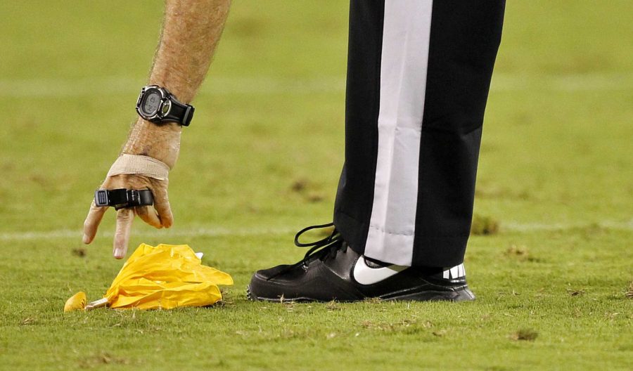 A referee picks up the yellow flag during the second half of an NFL preseason football game between the Denver Broncos and the Arizona Cardinals, Thursday, Aug. 30, 2012,in Glendale, Ariz. (AP Photo/Matt York)