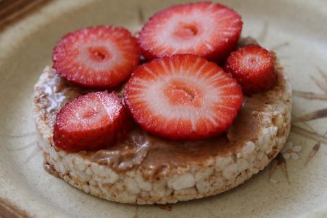 Sliced strawberry on a bed of almond butter spread across an organic rice cake, crispy, sweet and nutty.