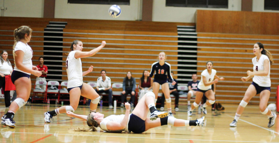 SRJC women's volleyball team members furiously block a spike from their opponent.