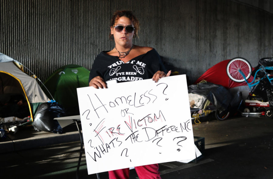 With garbage bins full of personal belongings, several activists helped the homeless recover their things. One woman displays her hand-made sign and protests the removal of their camp.