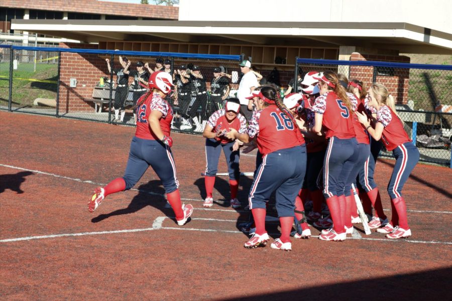 Alexis Gumanday's team congratulates her at home plate after hitting a home run during their win Feb. 3.