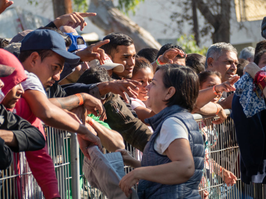 Migrants reach for volunteers giving clothing in hopes of gaining their attention. 