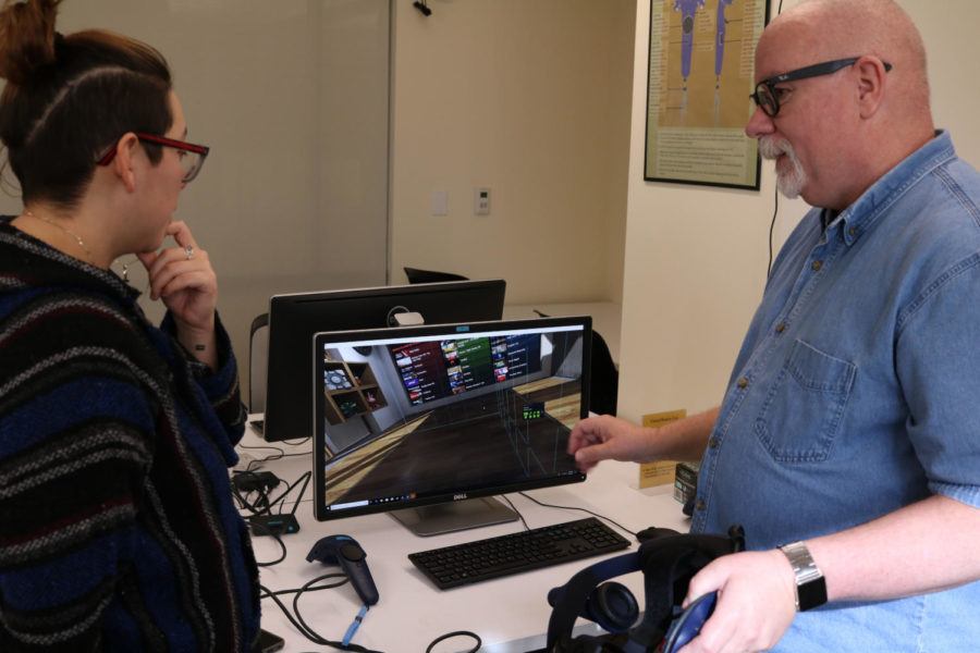 Instructor Robert Grandmaison teaches student Vanessa Mondragon how to use the Virtual Reality gear, available for student use in the new Digital Media Suites on the 2nd floor of Doyle Library.
