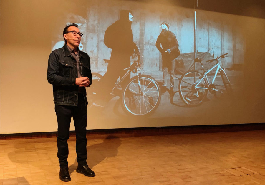 Erik Castro, photojournalist and presenter, answers questions about his 14-month project, "Broken," noon Feb. 12 in the Newman Auditorium, with his photo of Steve and Michelle going for a late night ride in the background. 