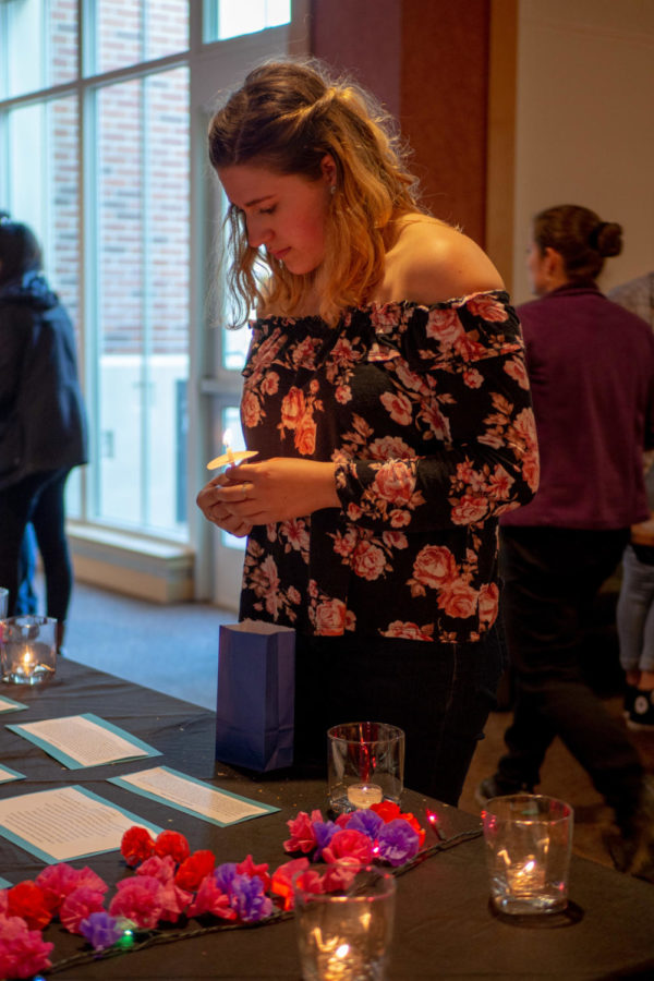 Sophie Ammerman, 20, SRJC psychology student holds a still-burning vigil candle as she reflects on the stories of sexual assault victims displayed on the vigil table.