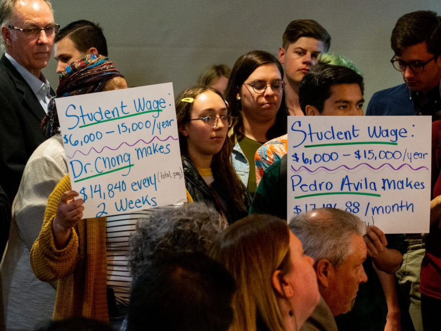 MEChA de SRJC members hold signs up toward the Board of Trustees to show their dissatisfaction in the boards current plan to increase student-employee wages before the April board meeting on Tuesday in the Student Activities Center.