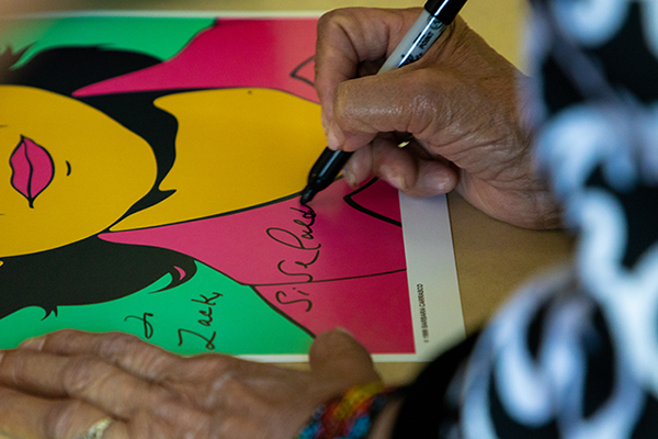 Huerta autographs a poster, adding her moniker in her own handwriting.