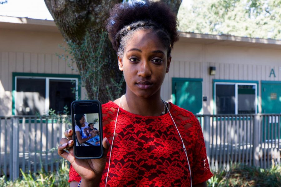 Anetra McCartney, 24, holds up a photo of her mother Sylvie McCartney and her newborn brother, Braden, radiating joy. McCartney lost contact with her family during Dorian and thought this photo could be their last. 