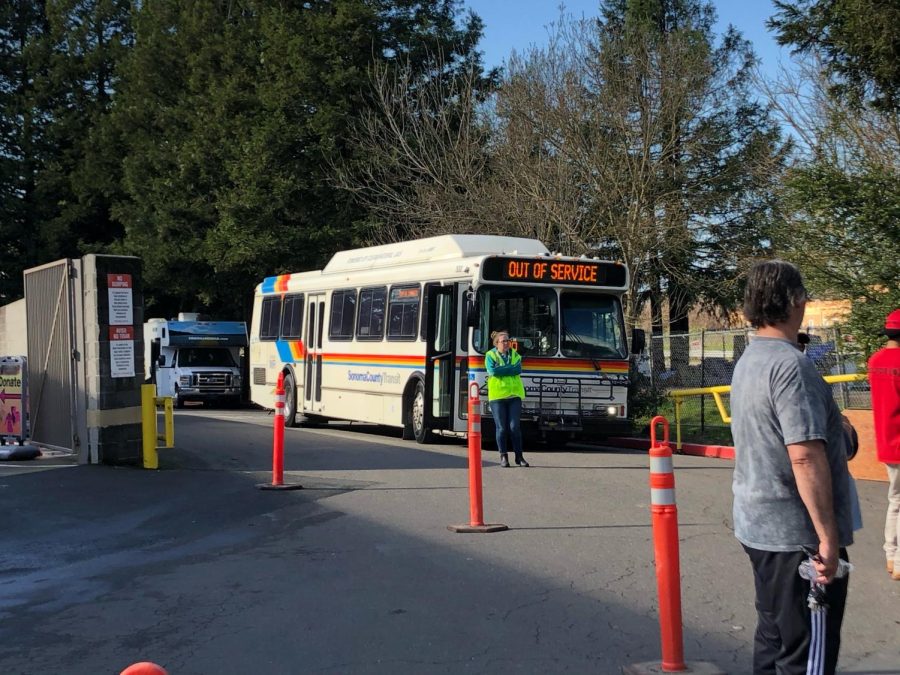 A county bus sits idle waiting to ferry homeless residents, who acquiesce to the county’s requests, to their new outdoor camp at Los Guilicos.