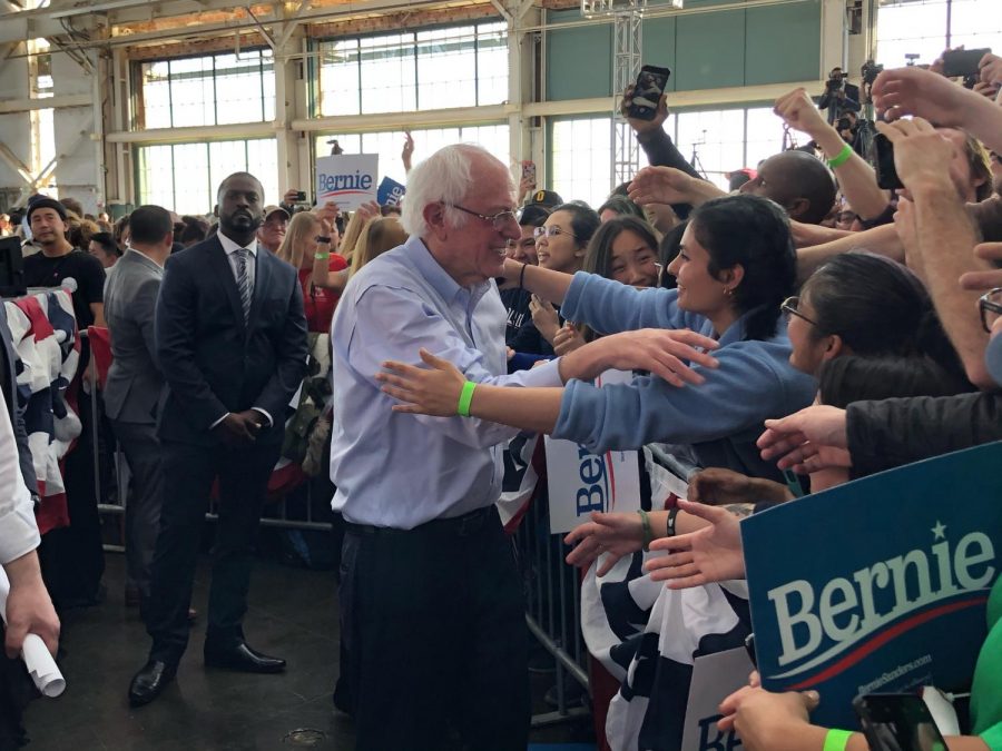 Senator Bernie Sanders embraces a loving fan at a recent rally in Richmond, CA. The energy in the crowd is electric as Sanders takes the time to shake hands and hug fans at the front of the audience.