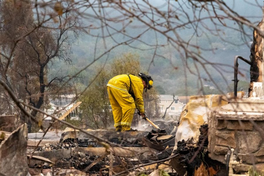 A firefighter digs through the ash of a home on Mountain Hawk Drive to prevent reignition. 