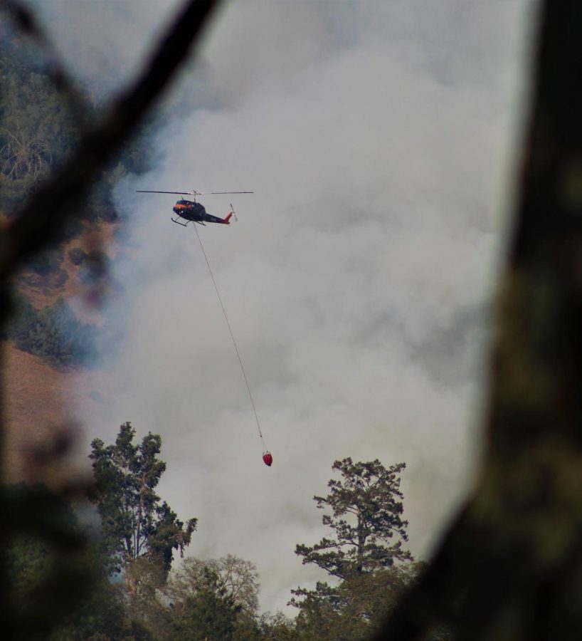 A helicopter carries water to douse the Glass Fire.