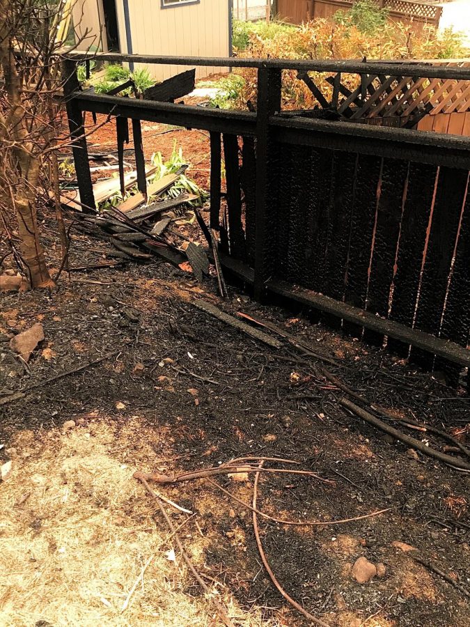 A burned fence sits outside a home on Los Alamos Road that survived.