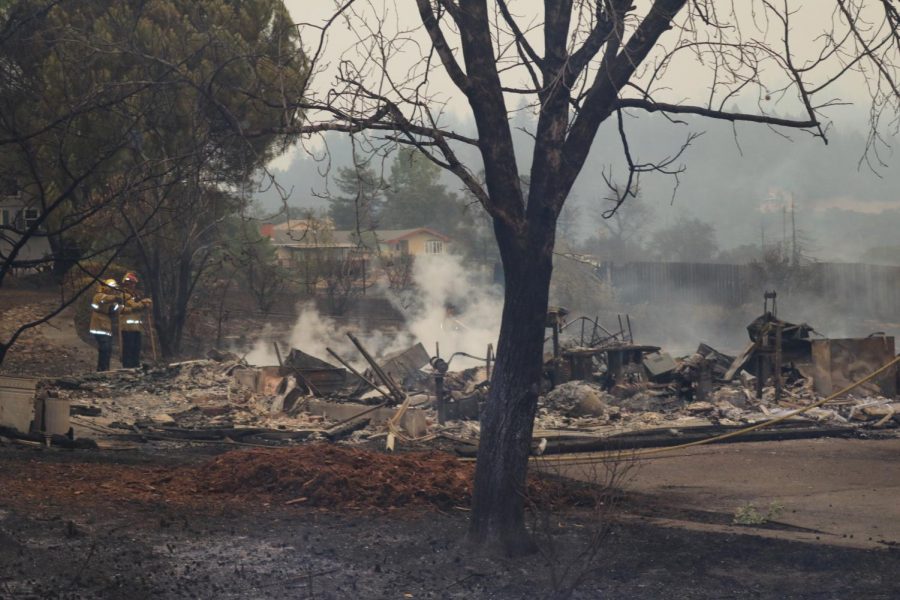 Two firefighters observe the smoldering remains of a house on Skyhawk Road.