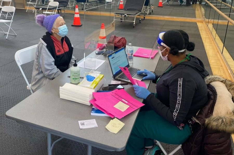 After receiving her first dose of the Pfizer vaccine, Stephanie Stone (left) sets her appointment for her second dose with nurses assistant Angel Rodgers (right).