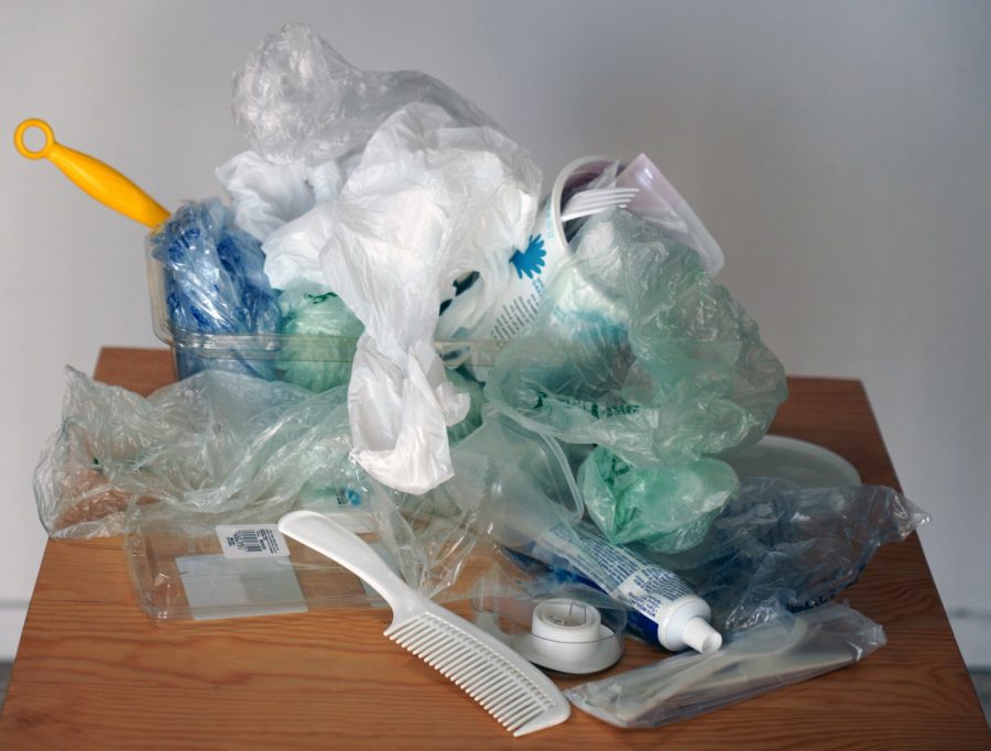 A pile of various pieces of unrecyclable plastic including shopping bags, water bottles and a comb.