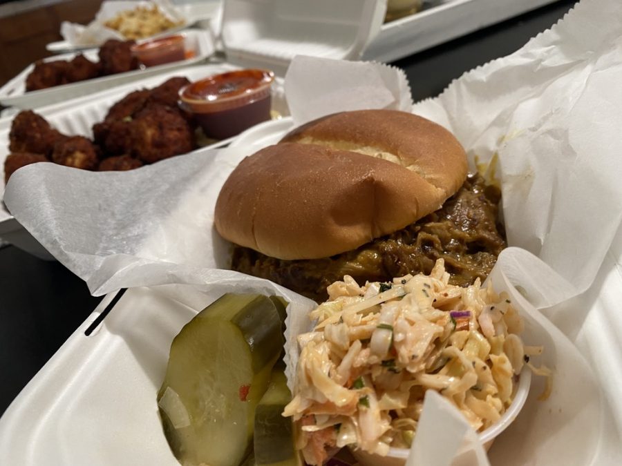 A pulled pork sandwich with a side of spicy coleslaw and a pickle.