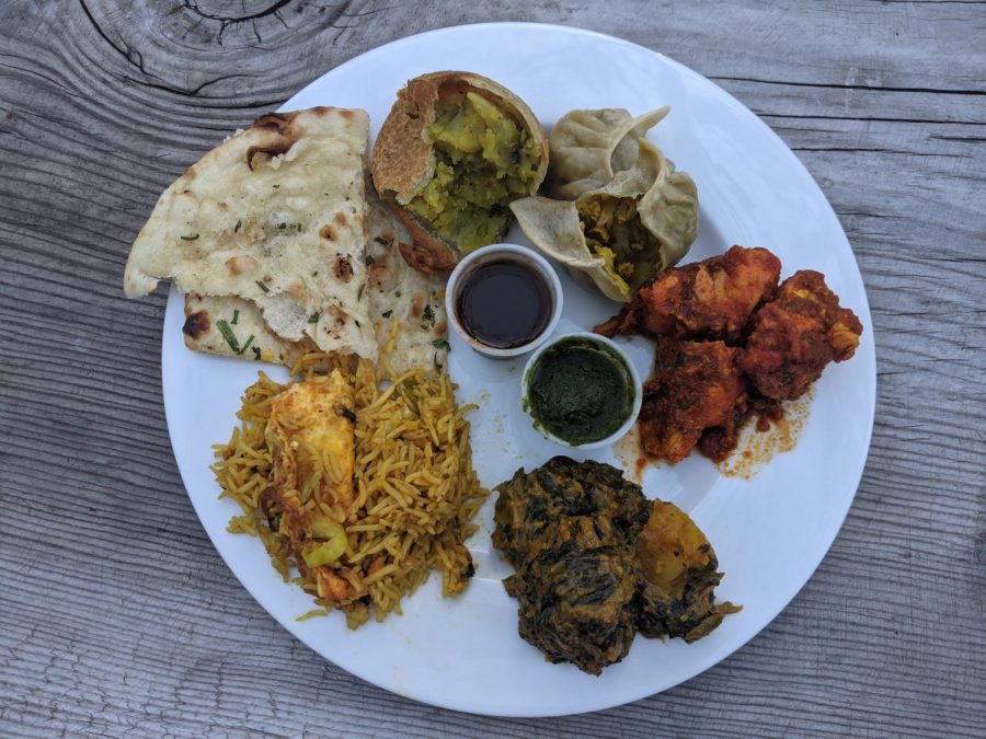 A plate filled with entree options from Cumin Restaurant including naan, chicken choila and aloo saag.