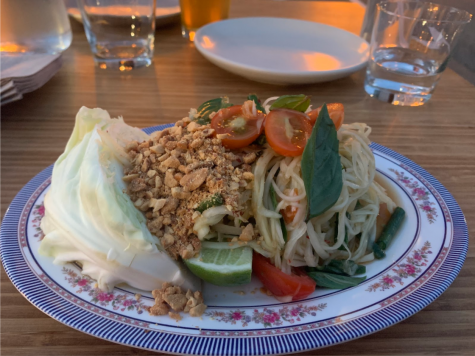 A plate of green papaya salad topped with peanuts and cherry tomatoes.