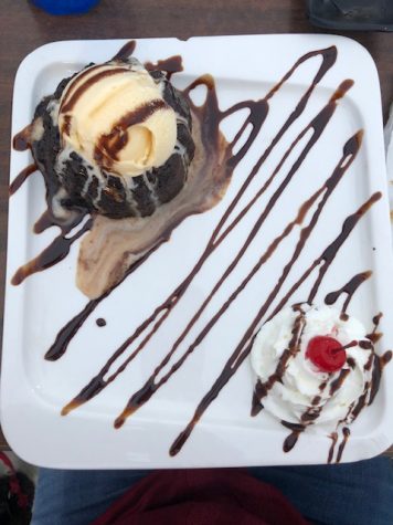 A picture of a plate with a chocolate lava cake and whipped cream drizzled in chocolate syrup.