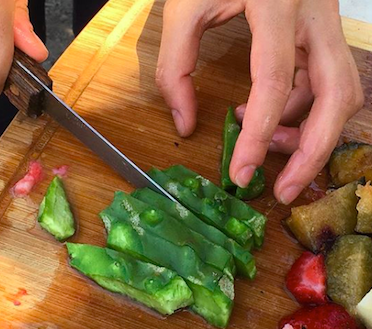 A close up of someone cutting nopales (cactus pads).