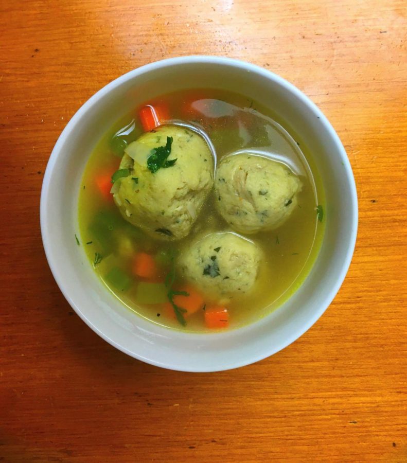 A bowl of matzo balls served in broth with vegetables.