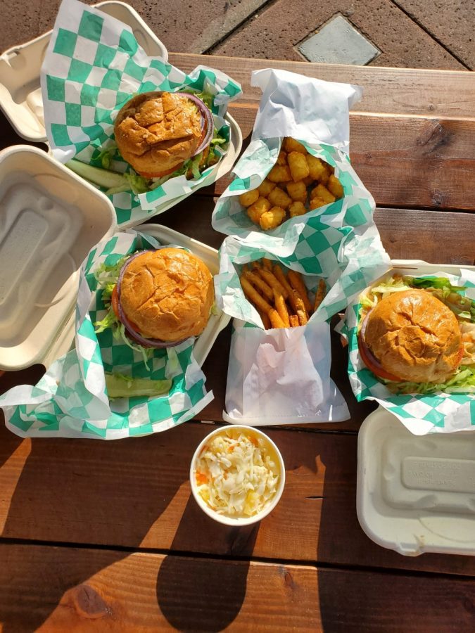 A+picture+of+plant-based+burgers+wrapped+in+green+and+white+paper%3B+pictured+with+a+side+of+french+fries%2C+tater+tots+and+pineapple+coleslaw.