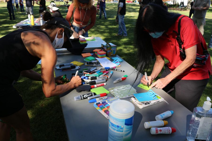 Participants write actions they commit to take to end systemic racism on sticky notes that will be added to a poster for accountability.