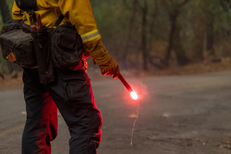 A firefighter strategically places his flare to complete a controlled burn on St. Helena Road during the Glass Incident fire.