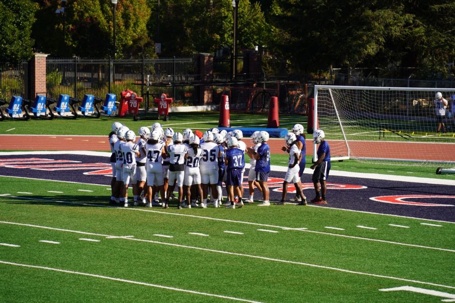 Santa Rosa Junior College football players huddled together wearing white uniforms/