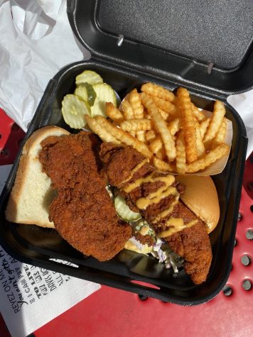 Chicken, mustard, fries, pickles and bread in a to-go container.