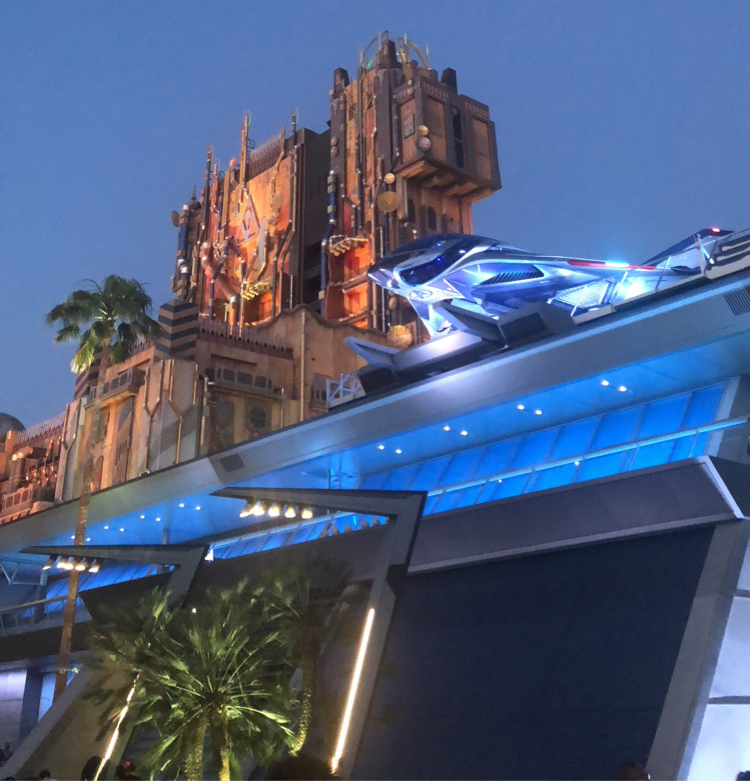 a photo after sunset of the Guardians of the Galaxy tower ride behind a futuristic railway at Disneylands California Adventure.