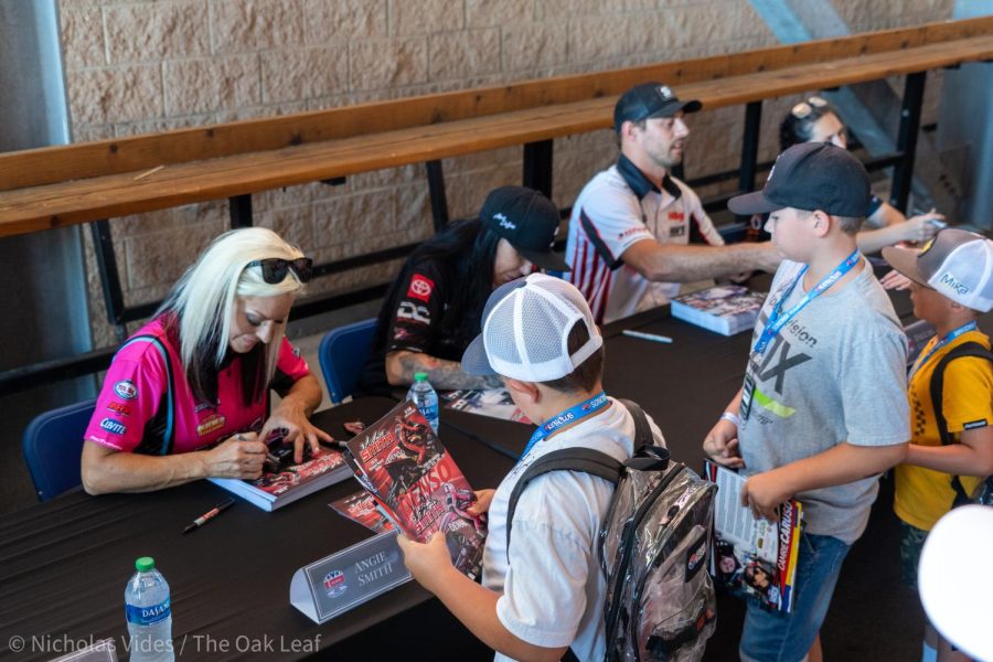 Pro Stock Motorcycle Racer Angie Smith  (left) signs autographs for kids at the Denso NHRA Sonoma Nationals on July 22, 2022.