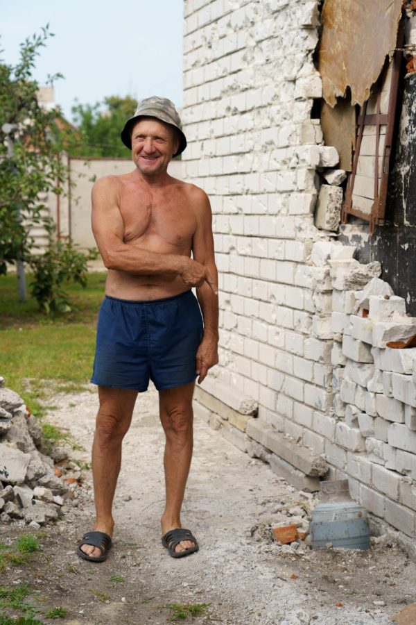 Oleksander Rubanok jovially points towards a missile that landed right next to his home in Malaya Rohan on Aug. 10, 2022.