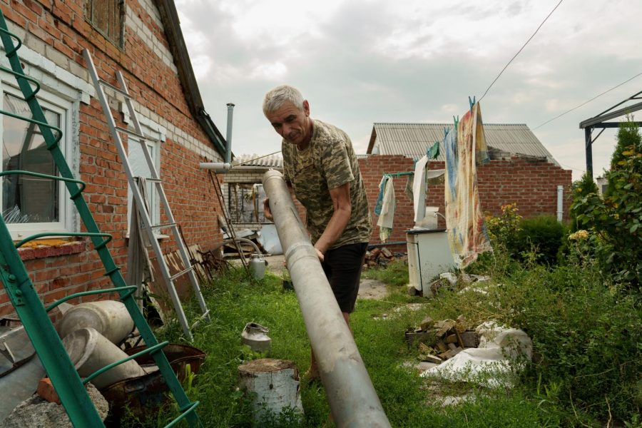 Hennadyi Balabonav drags a missile casing from his backyard, where he has a small pile of missiles and shells that have landed on his property on Aug. 10, 2022 in Malaya Rohan, Ukraine.
