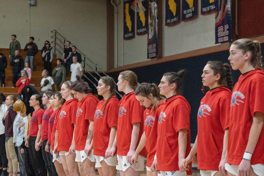 The SRJC Women's Basketball team hold hands during the national anthem before the game against Laney College Saturday, March 4.