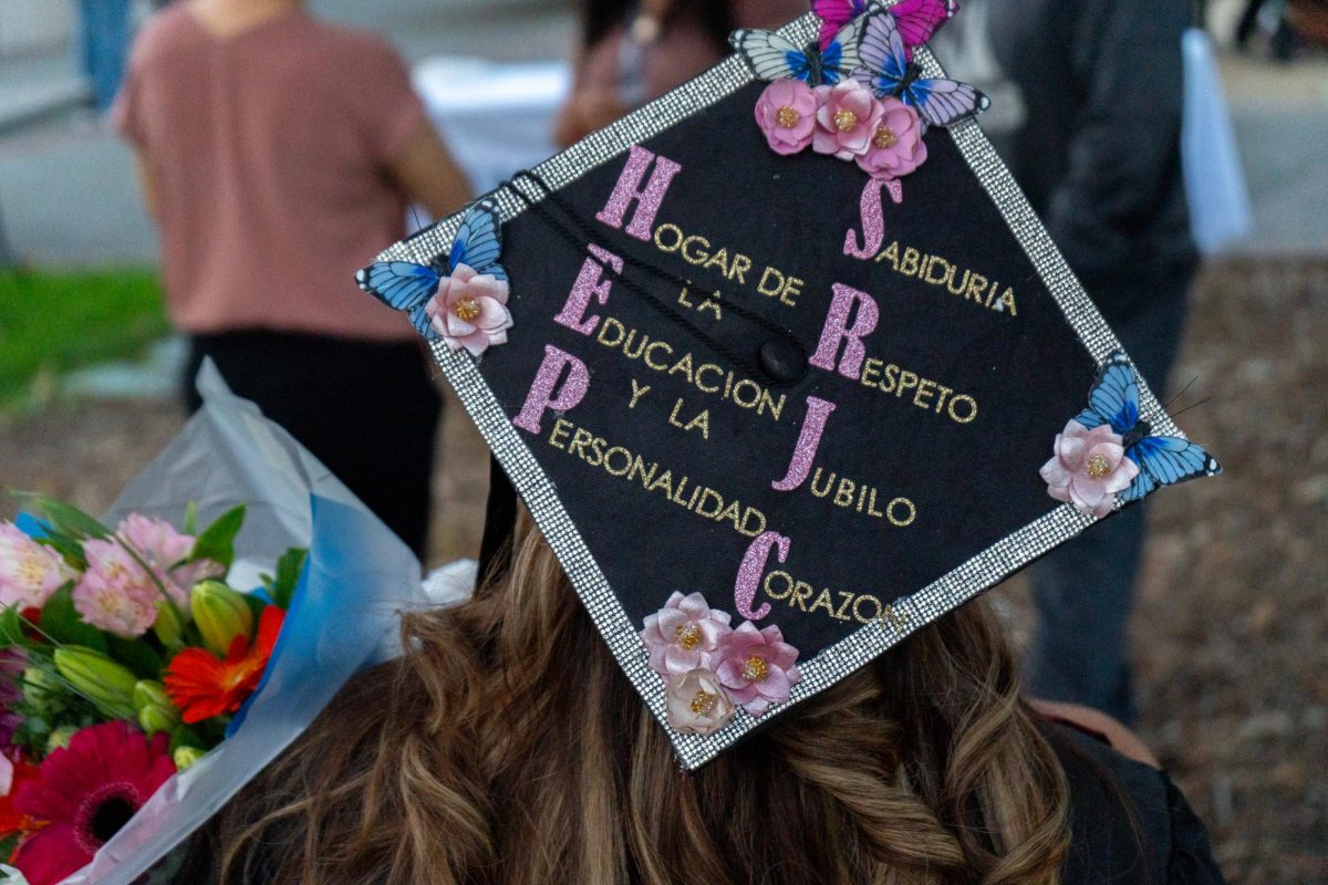 Lourdes Jimenez wears a cap that reads Hogar de la Educacion y la Personalidad, Sabiduria, Respeto, Jubilo, Corazon, which translates to Home of Education and Personality, Wisdom, Respect, Rejoice, Heart.