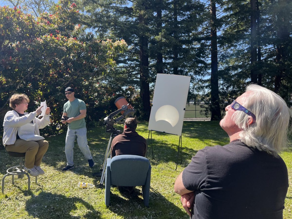 SRJC astronomy instructor Kieth Waxman used a telescope pointed at the eclipse to project an image of the eclipse onto a white piece of cardboard. Onlookers gaze to the heavens to see the eclipse in progress.