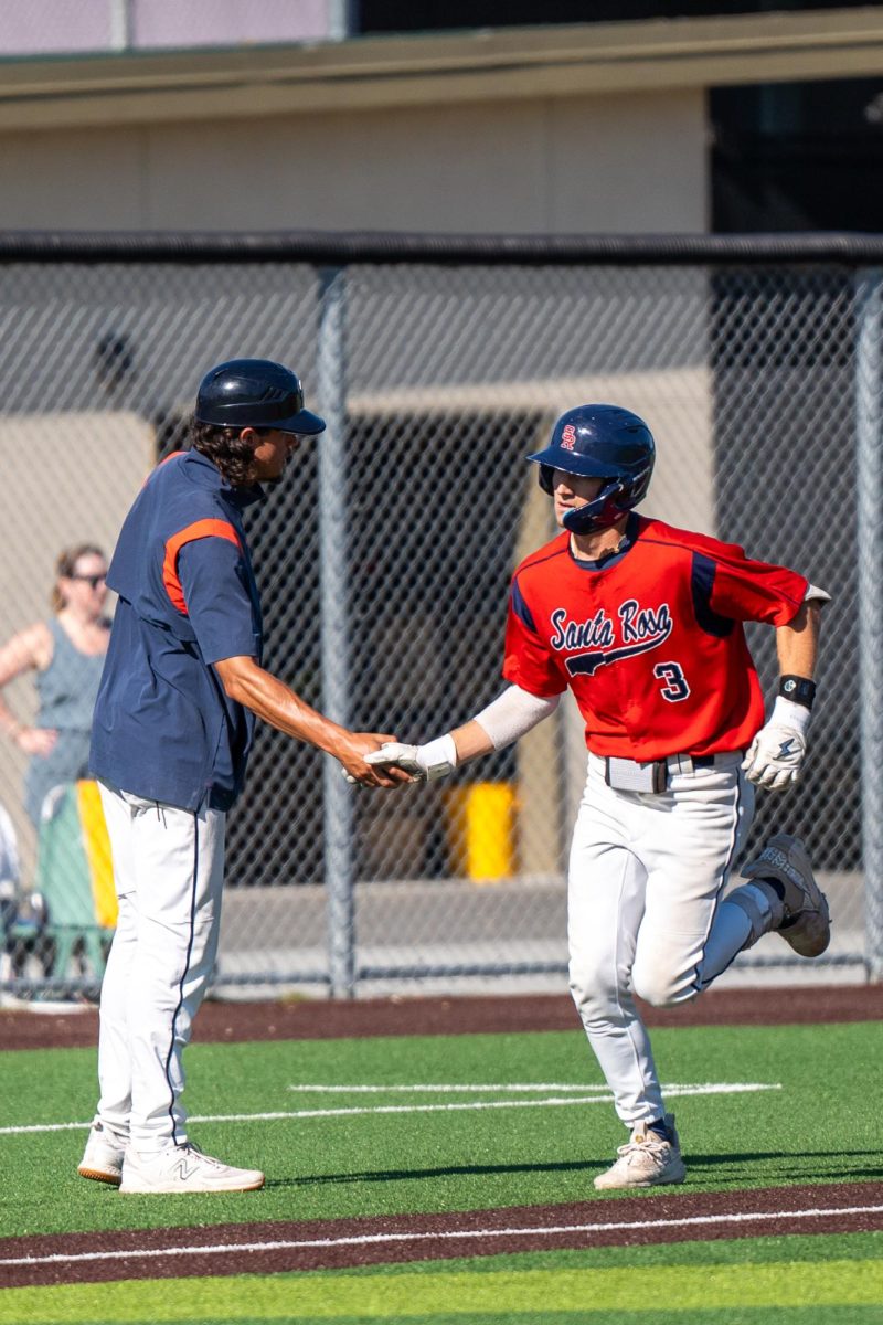 Shortstop Aidan Lombardi shakes third base coach Jeff Bart's hand on his way to home plate after a home run in the bottom of the seventh secures two more runs against Chabot College in the second round of the CCCAA Super Regionals in Hayward on Thursday, May 9, 2024.