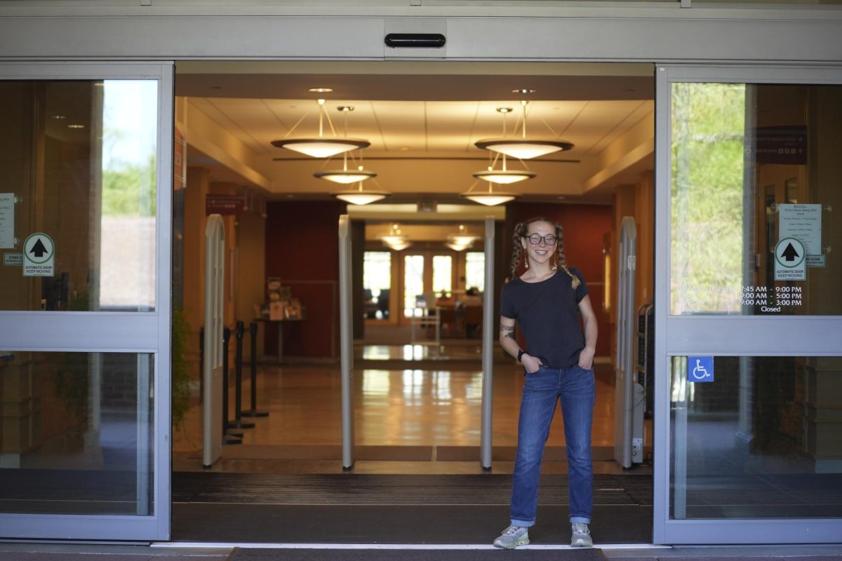 Genaveve Clendenen, a student worker, poses in the entrance to Doyle Library, where she works to loan students laptops, chargers, books and chargers, among other resources.