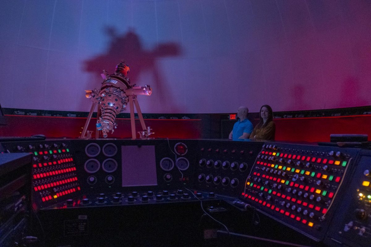 Instructors Keith Waxman and Laura Sparks show off the planetarium's control panel, which is entirely analog. Each button and switch connects to a series of relays.